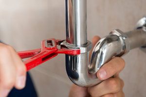 Plumber using pipe wrench on sink plumbing