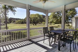 Covered wood patio overlooking grassland and trees